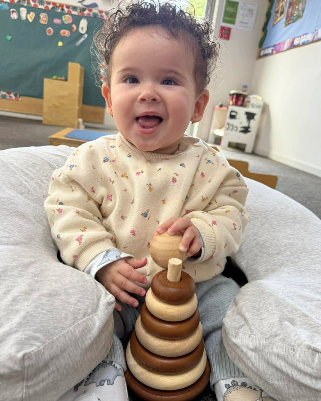 A happy child playing with a wooden Montessori stacking toy at Lilchamps